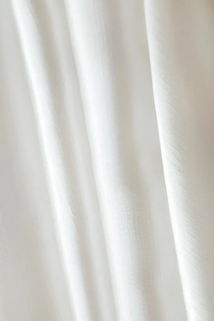 Detailed close-up of a white fabric with soft, flowing texture, perfect for backgrounds.